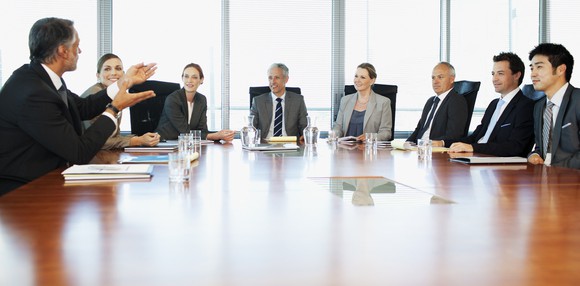 executives sit around a boardroom table having a discussion