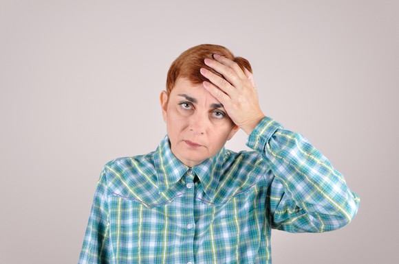 Woman holding her head, looking sheepish