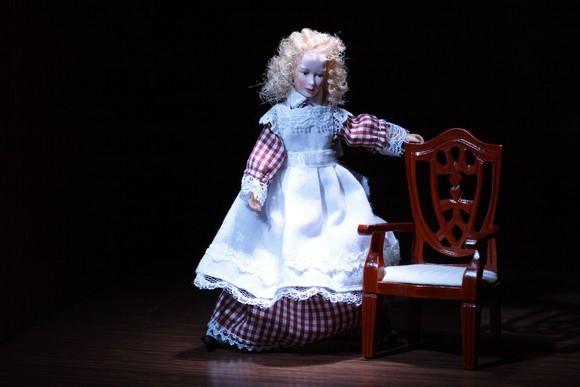 Doll standing next to chair.