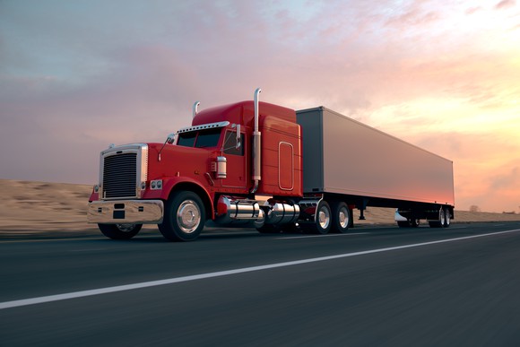 Truck driving down the highway at sunset.