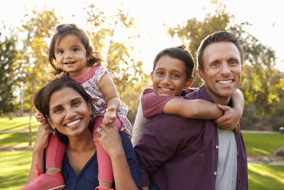 Man and woman carrying children on their shoulders