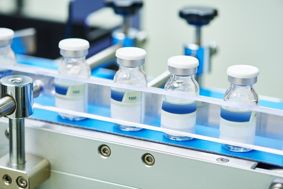 Several bottles of drug products on a manufacturing line.