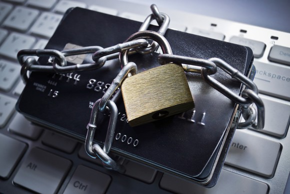 a bunch of credit cards tied up in a chain with a padlock, sitting atop a keyboard