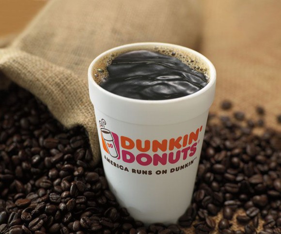 A cup of Dunkin' Donuts coffee sits in coffee beans.