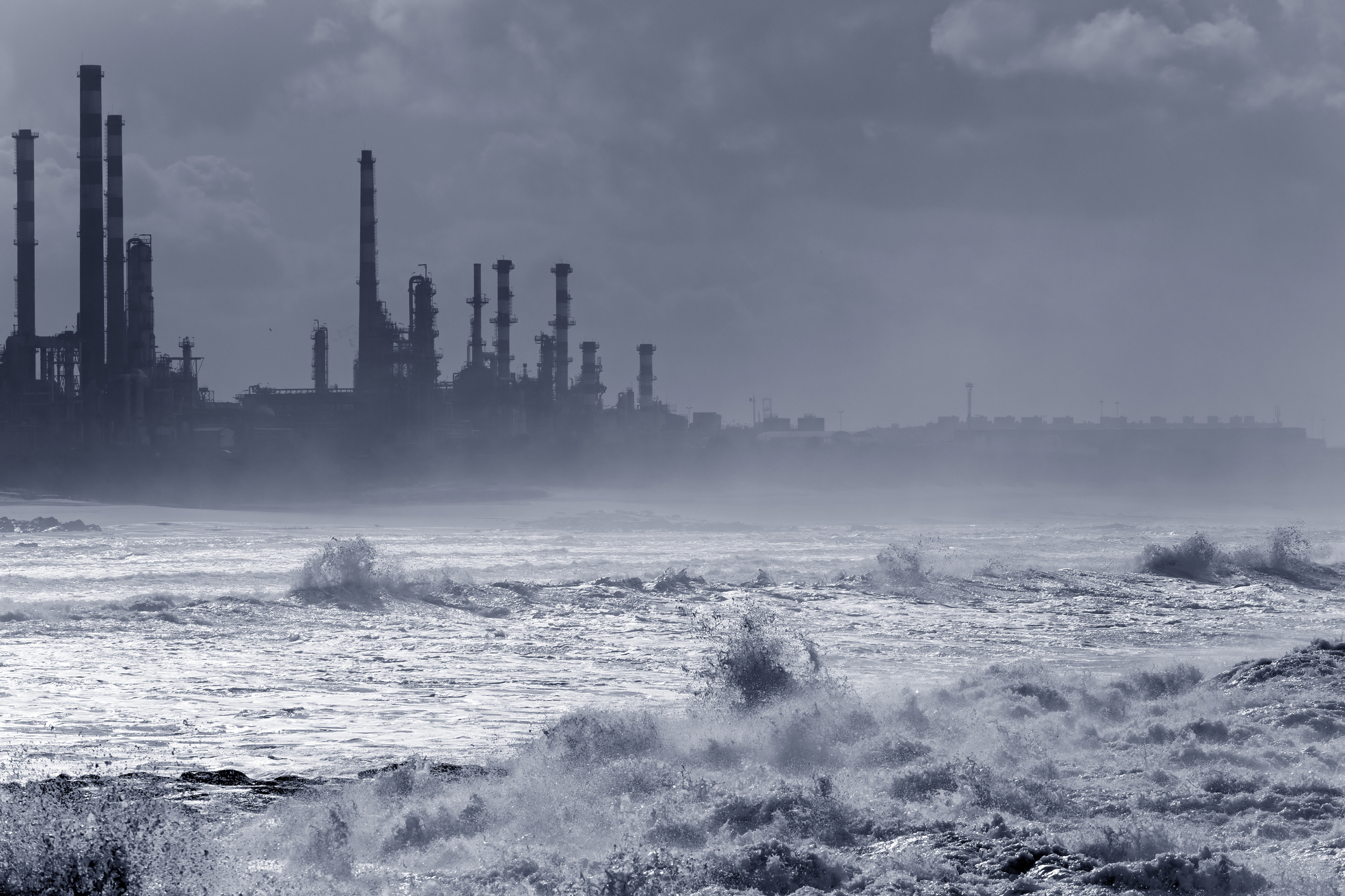 A storm hitting an oil refinery by the sea.