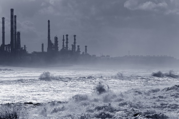 A storm hitting an oil refinery by the sea.