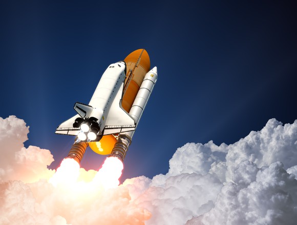 Space shhuttle and booster rockets just clearing the cloud cover on their way to space.