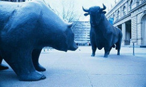 Picture of a life-size bull and bear statues on a city sidewalk.