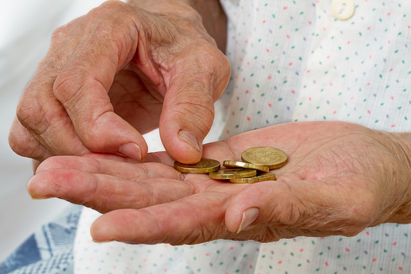 Close-up of an old woman's hands counting gold coins.
