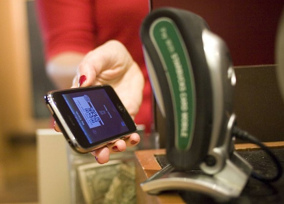 A woman uses her mobile device for payment at a Starbucks.