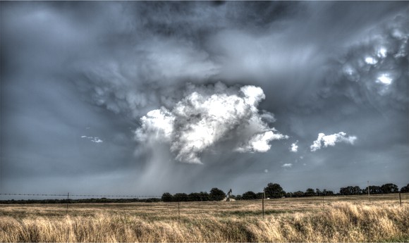 An oil well with storm clouds above.