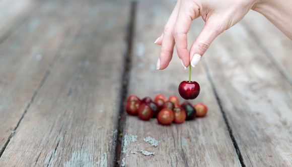 A hand picking a cherry from a table.