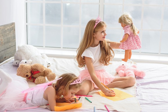 Girls playing with a doll while coloring