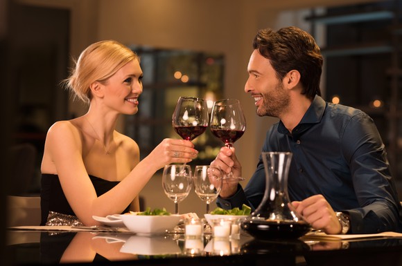 Dressed-up couple toasting over red wine at restaurant