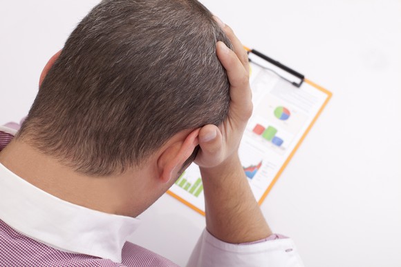 Person making a frustrated gesture while looking at a collection of charts.