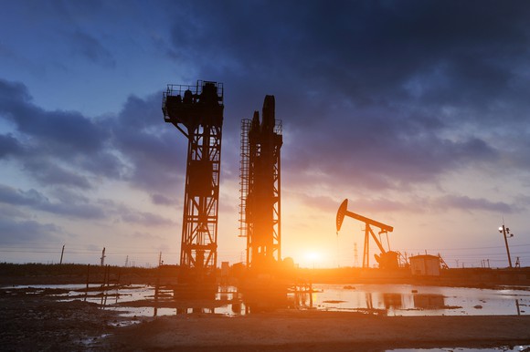 An oil field after the rain with the sun setting in the background.