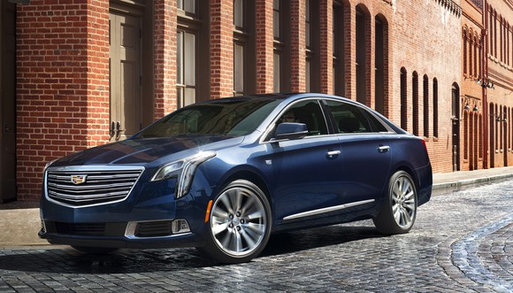 A dark blue Cadillac XTS sedan parked on a cobblestone city street.