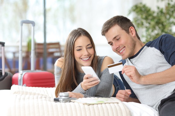 Two tourists with travel bags booking a hotel online