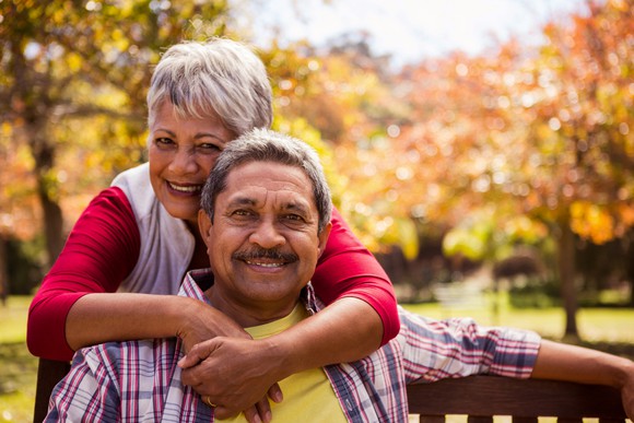 Senior woman putting arms around senior man outdoors
