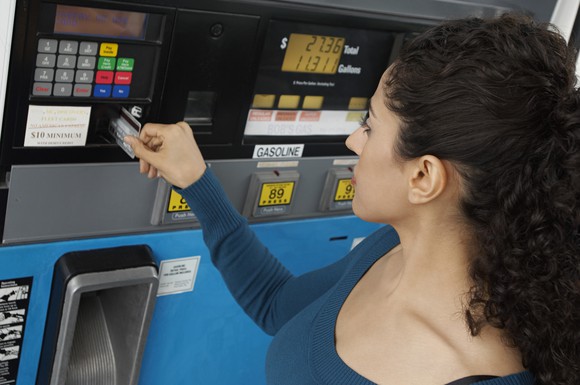 A woman paying with a credit card at gas station pump.
