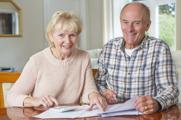 A smiling elderly couple reviewing their finances.