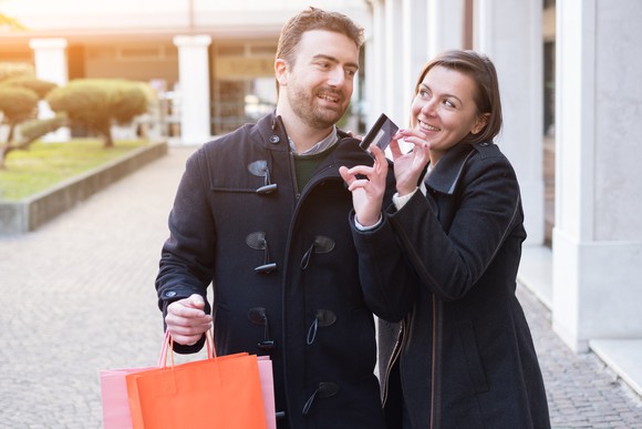 young couple shopping with both hands on a credit card