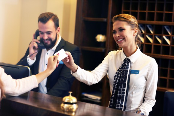 A hotel concierge hands a cardkey to a guest.