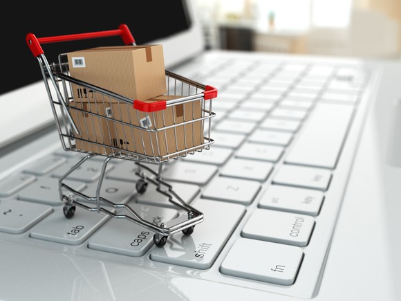A small shopping cart filled with boxes on top of a computer keyboard