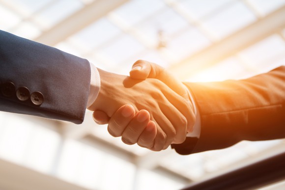 Close-up on a handshake between two men in business suits.