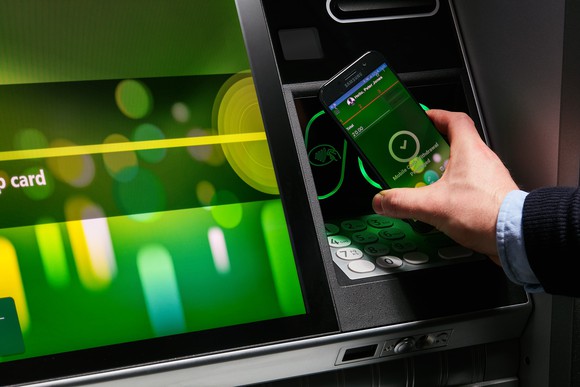 A person using a mobile device at an ATM.