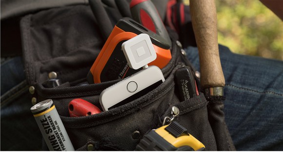 A toolbelt with a Square credit card reader attached to a mobile phone.