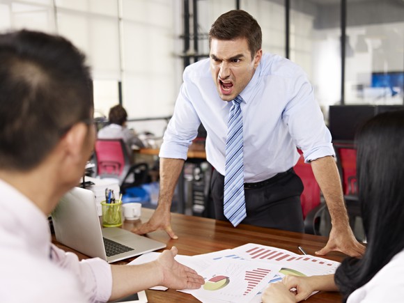 A man yells at another man in an office.