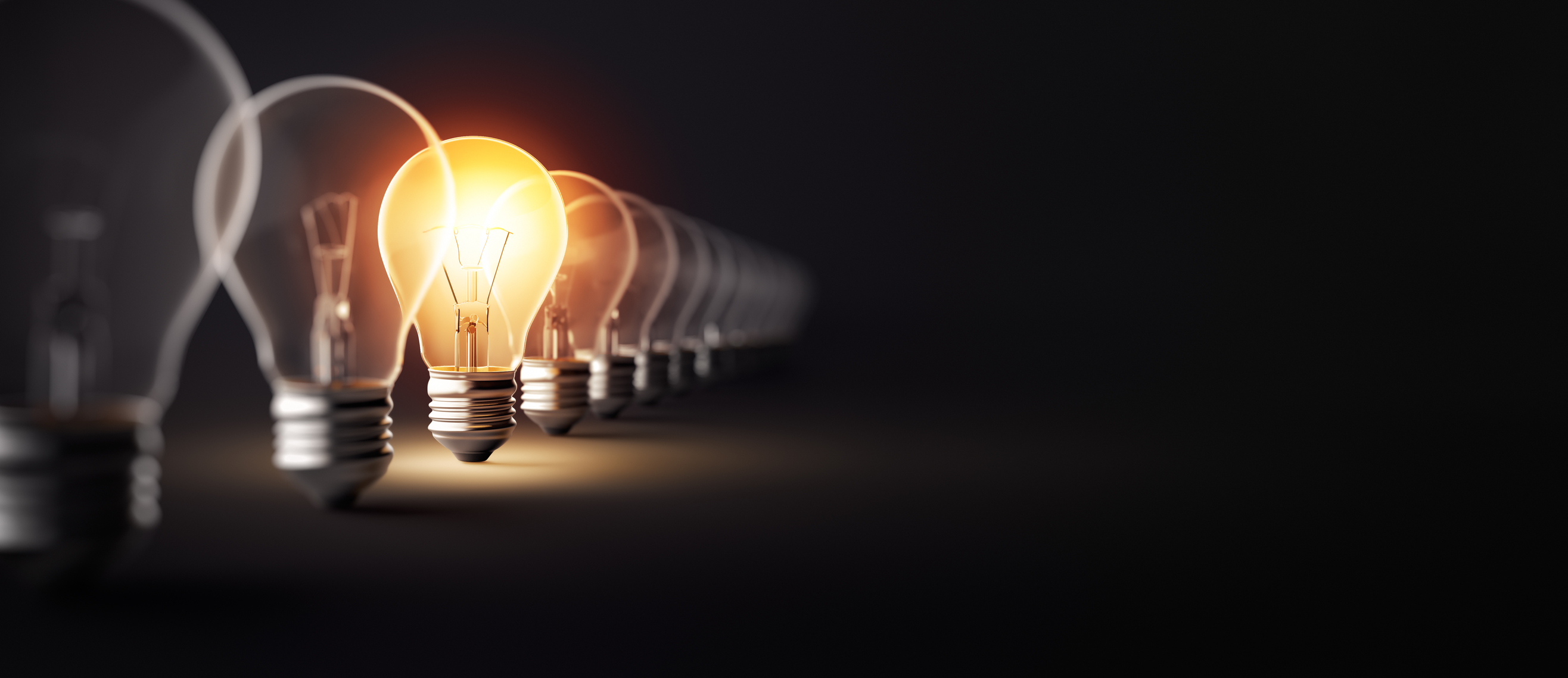 A row of Edison-style light bulbs with one lit.