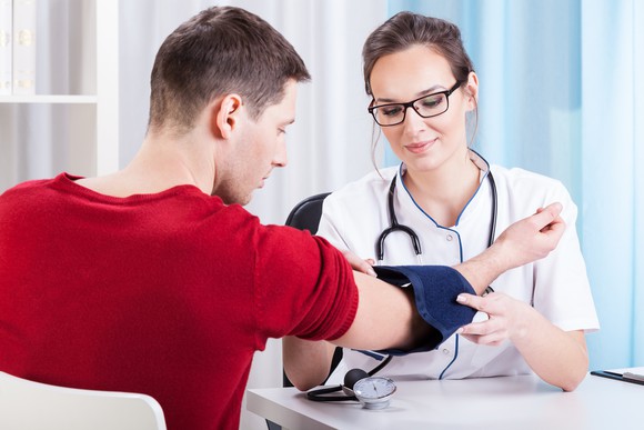 Doctor checking man's blood pressure