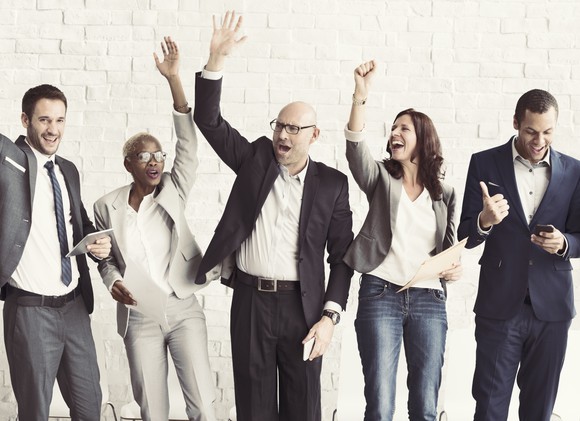 A group of people in business attire, being enthusiastic.