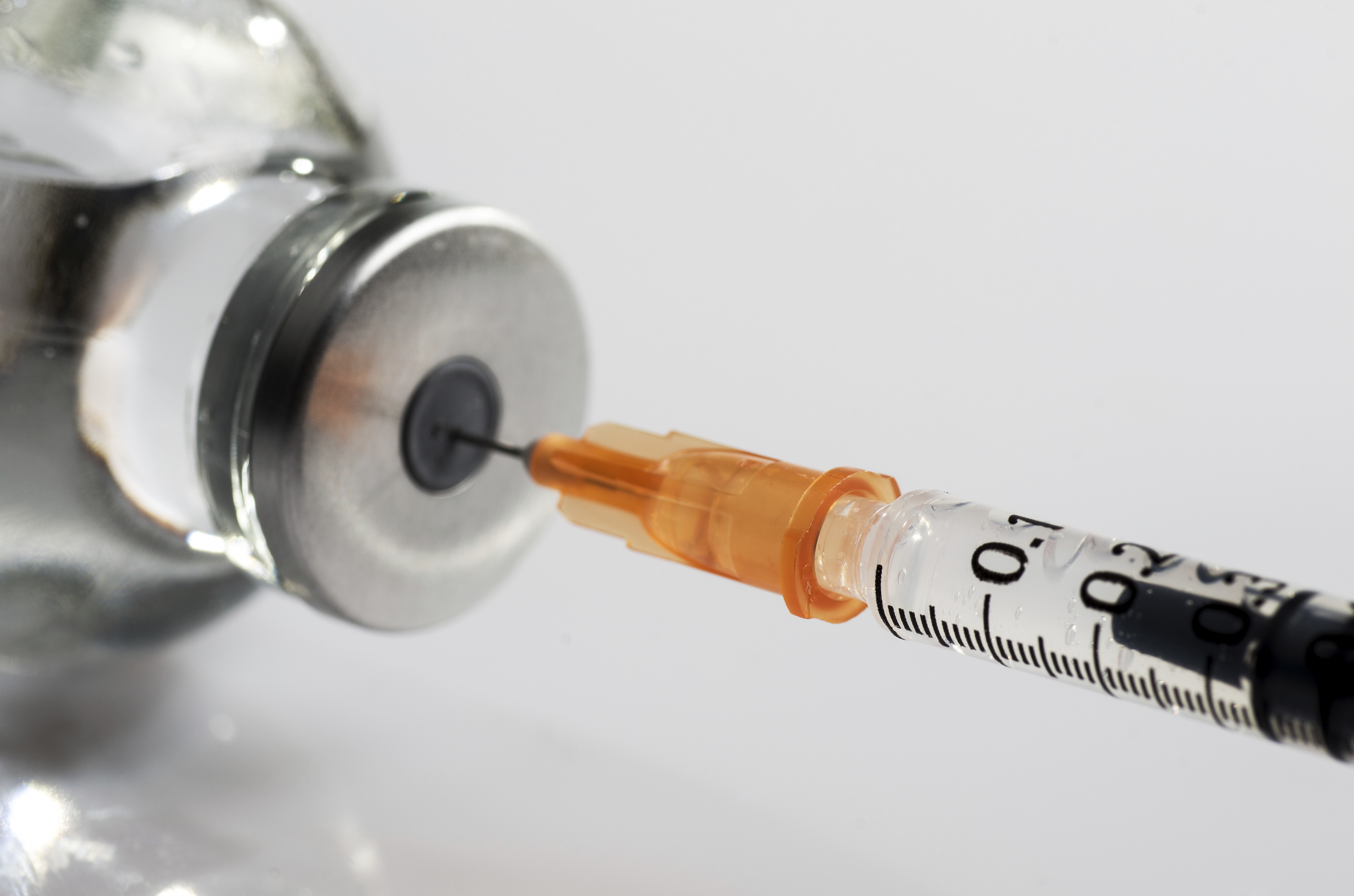 Syringe in a vial pulling out fluid
