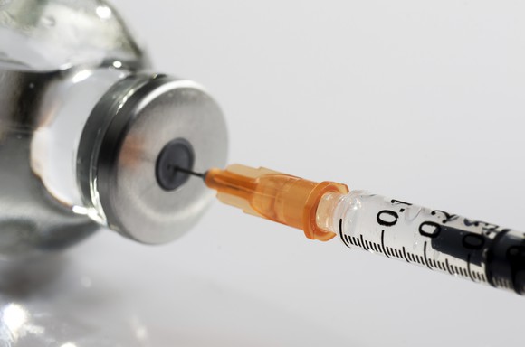 Syringe in a vial pulling out fluid