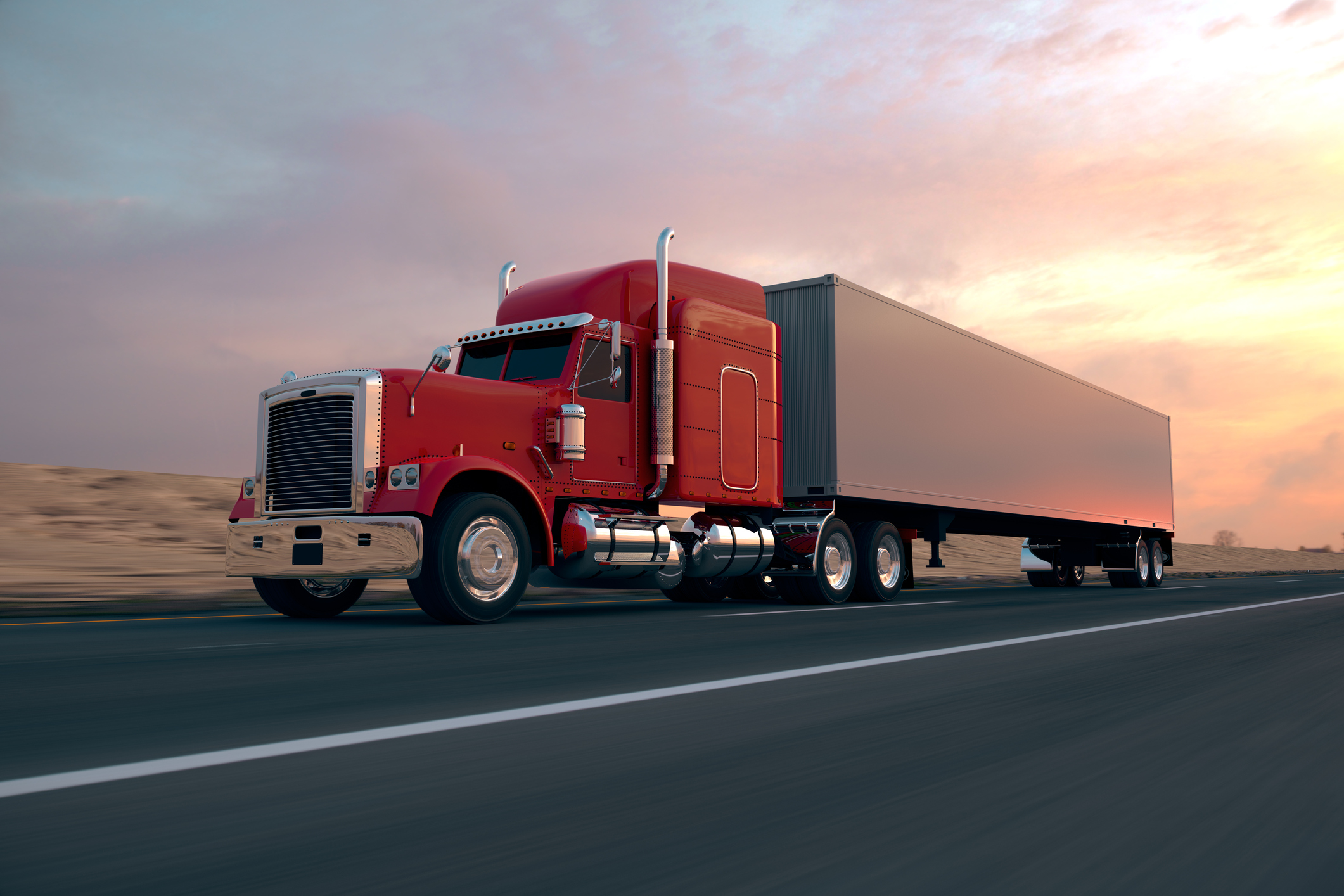 A truck driving on a highway at sunset. 