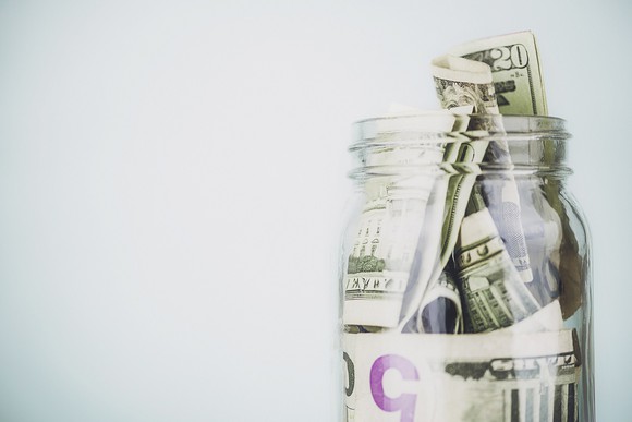 A glass jar stuffed full of U.S. currency