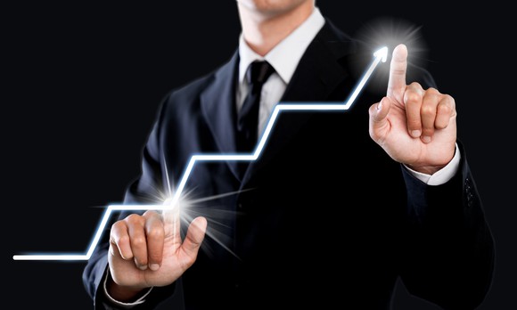 Businessman pointing to low point on line chart and to arrow going up