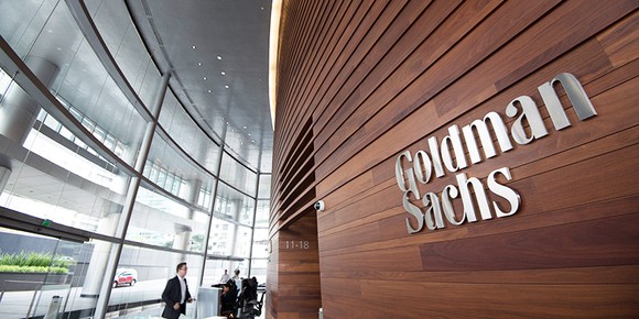 Goldman Sachs logo on wood wall in lobby of office building.