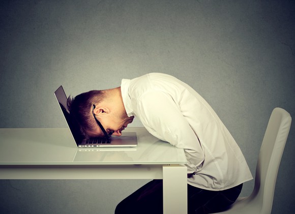 Man resting his head against a laptop