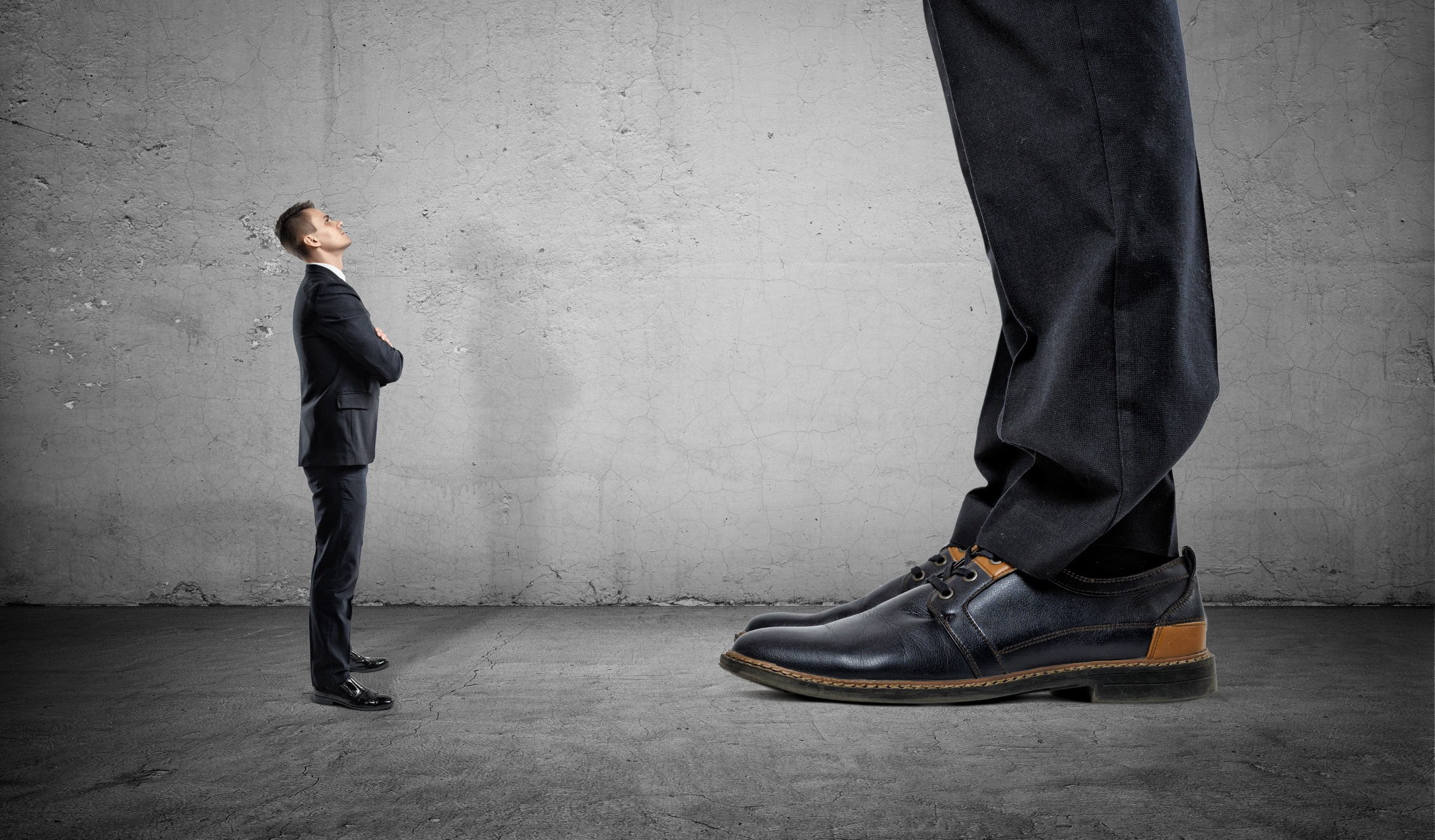 A man in business clothing looks up at a giant.