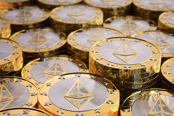 Numerous shiny gold/silver coins with Ethereum symbol on them.