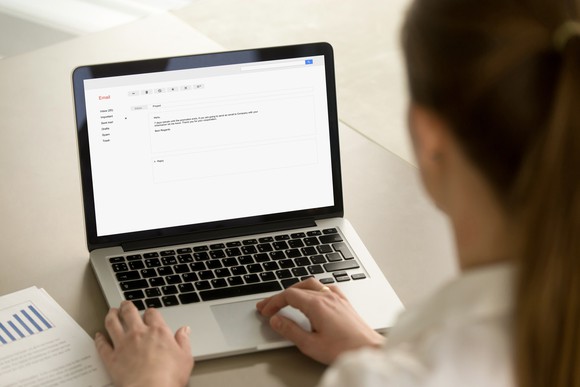 Woman typing an email on a laptop.