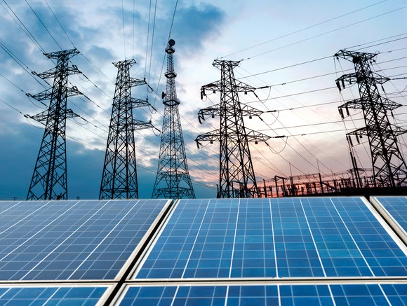 Solar panels with transmission lines in the background.