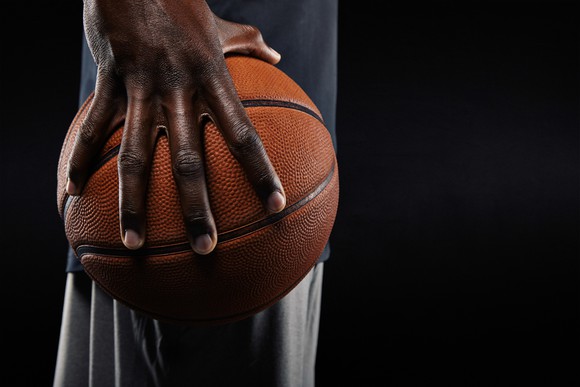side shot of man holding basketball in one hand