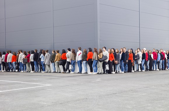 People waiting in line outside of a store.