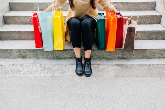 Someone sitting on concrete steps surrounded by shopping bags.