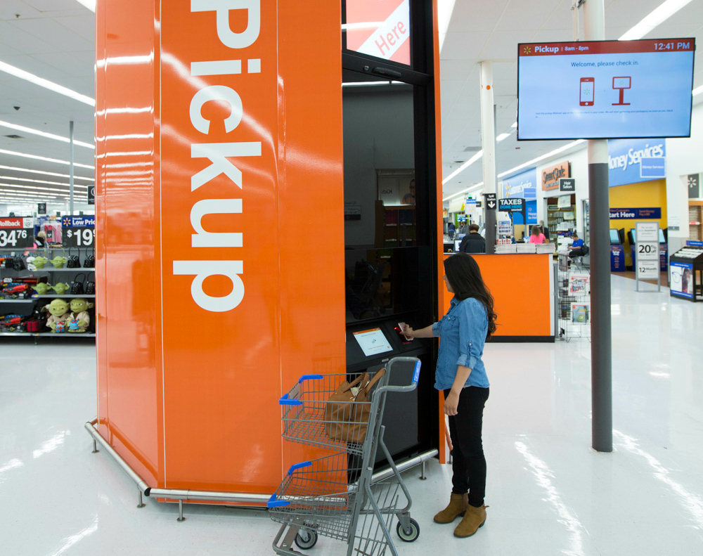 A woman with a shopping cart accesses an in-store Wal-Mart pickup tower.